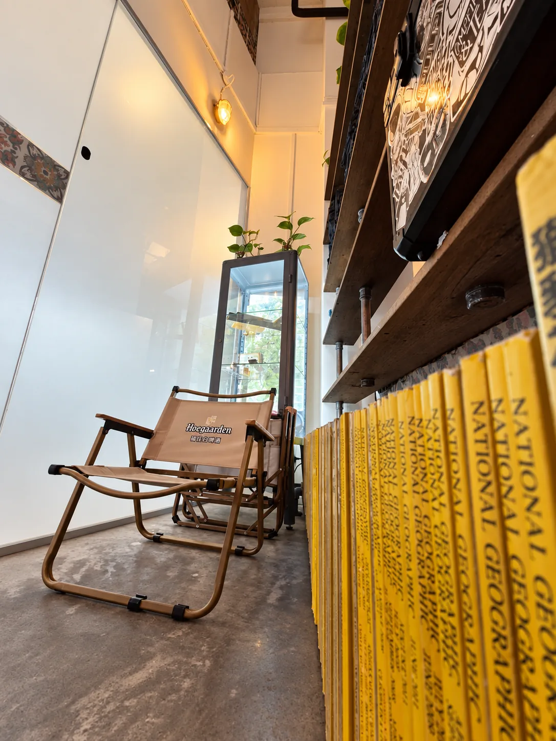 A folding camp chair beside a shelf lined with a full run of yellow-spined National Geographic magazines.